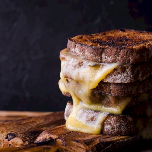 A brownie or cake slice with a creamy frosting layer on top, plated on a dark surface, close-up shot.