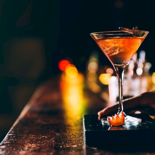 A small illuminated statue or figurine sits near burning candles in a dark setting, likely part of a decorative or ritual display.